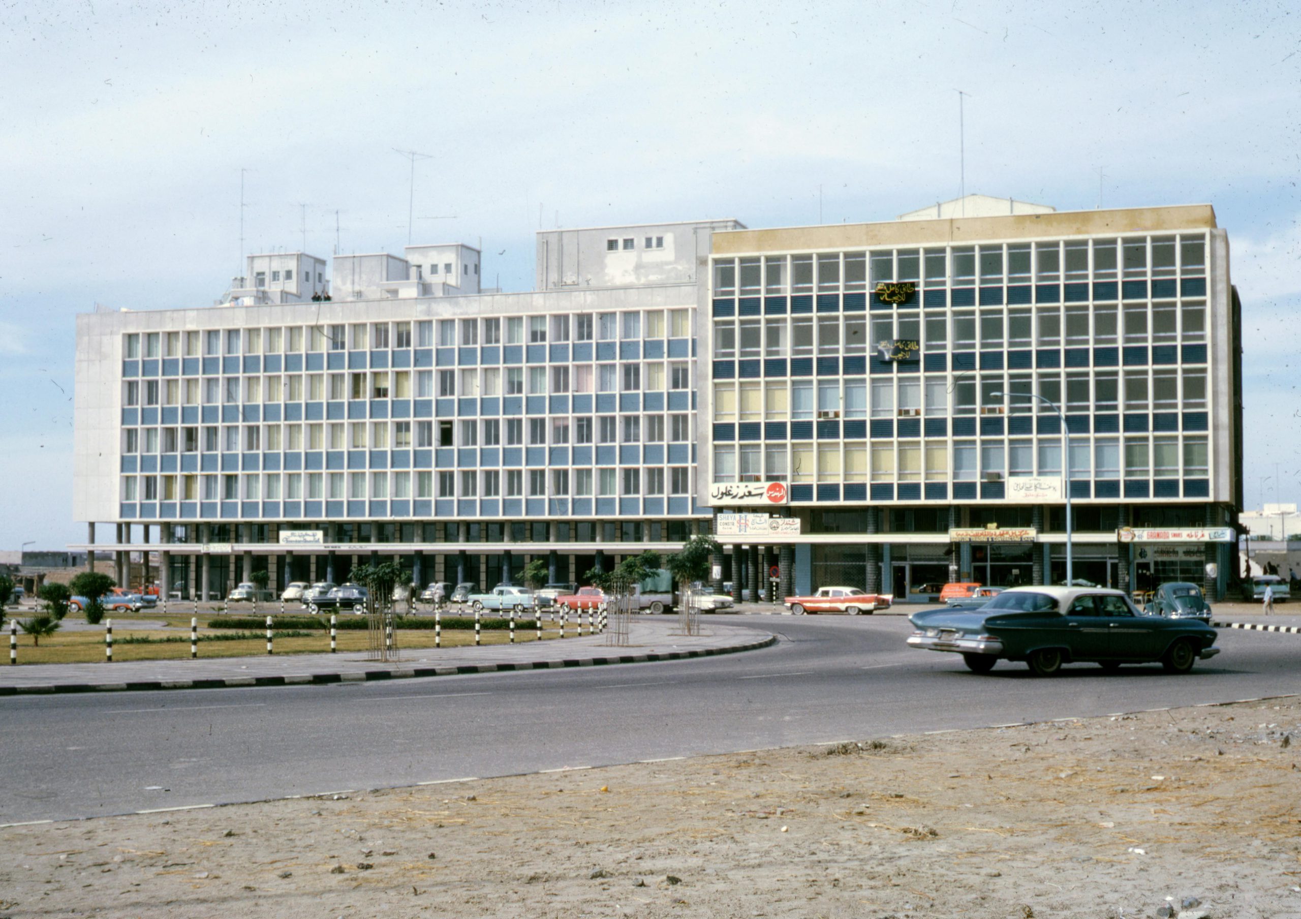 Vintage urban setting featuring mid-century architecture and classic cars during the daytime.