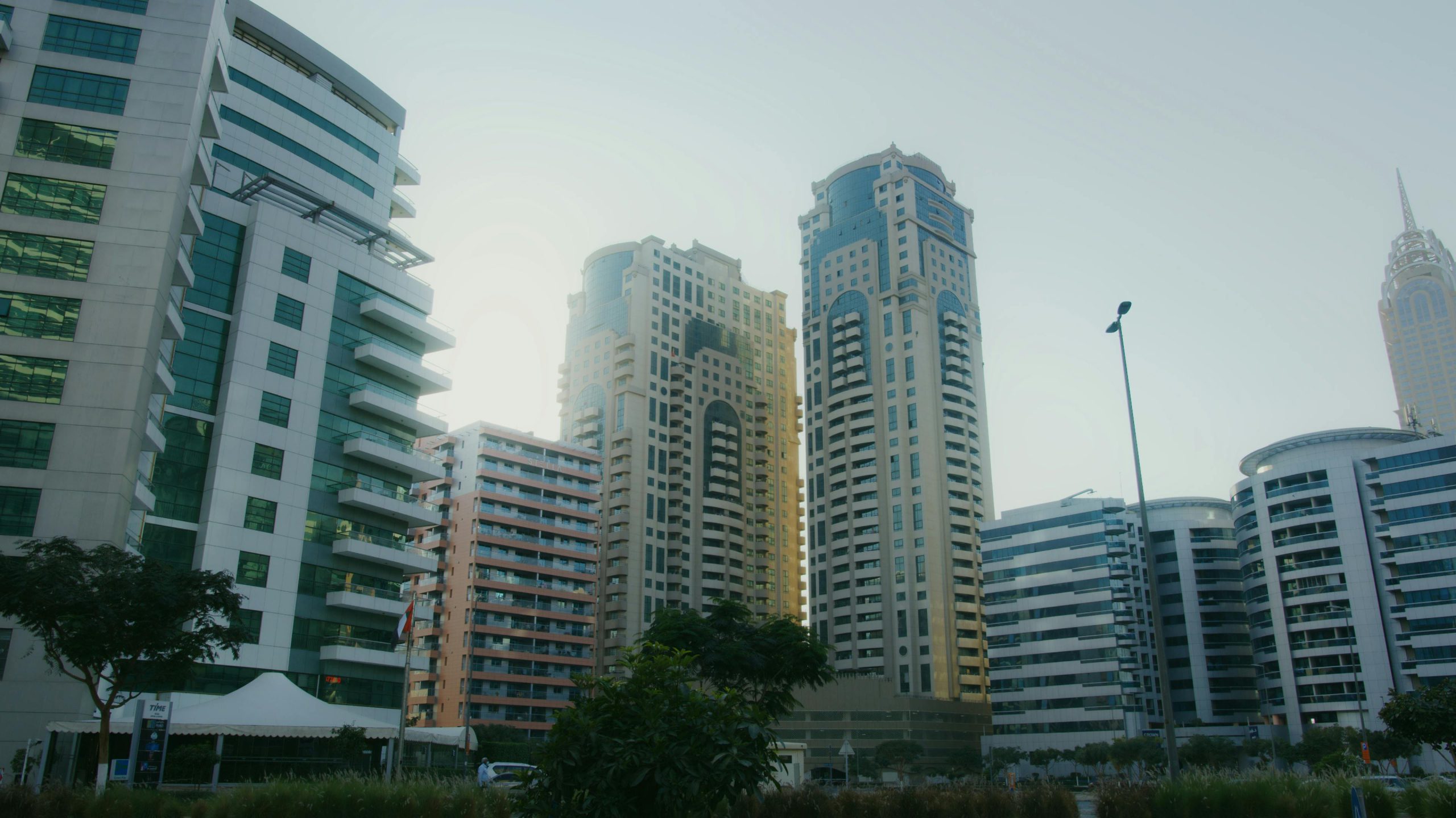 Dynamic cityscape featuring high-rise buildings under a blue sky, capturing modern urban architecture.